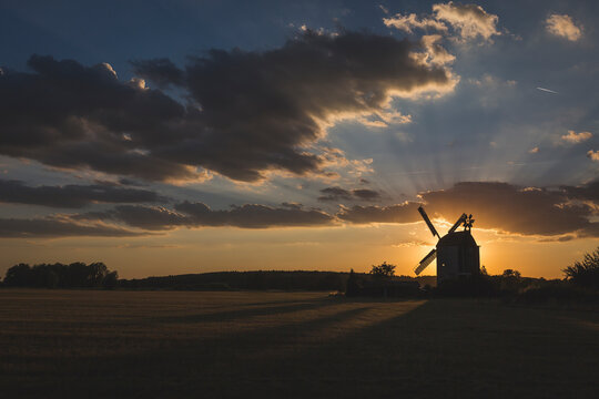 Germany,ÔøΩBrandenburg, Gray clouds over silhouette of countryside windmill at sunset