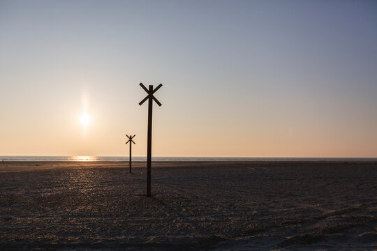 Denmark, Romo, Silhouettes of distance markers on coastal beach at sunset