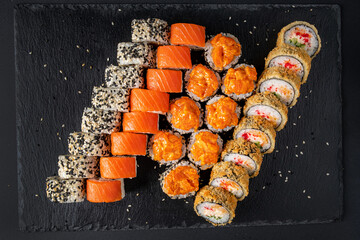 Assortment of fresh prepared sushi on black background.