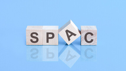 SPAC symbol. Wooden blocks with words 'SPAC, special purpose acquisition companies' on beautiful blue background, copy space. Business concept.