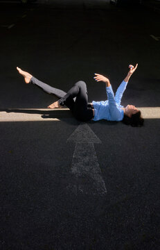 Woman lying on back in stripe of light moving arms and legs