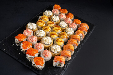 Assortment of fresh prepared sushi on black background.