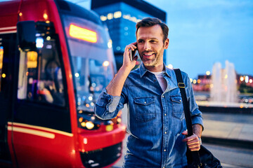 Man making phone call on smartphone with tram in the background