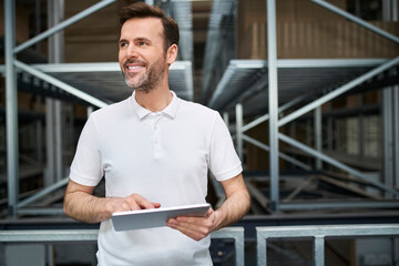 Smiling man using tablet in a factory