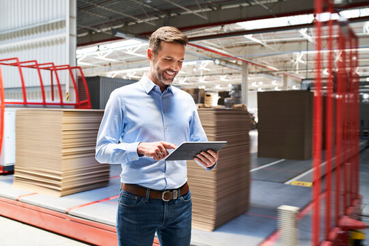 Smiling businessman using tablet in a factory