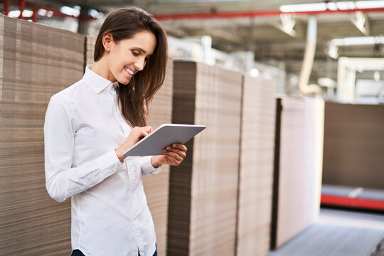 Smiling young woman using tablet in a factory warehouse