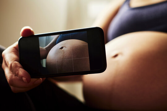 Pregnant woman taking a photo of her baby belly