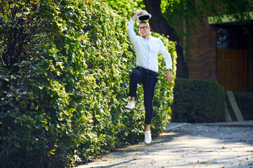 Happy young man jumping around at a hedge