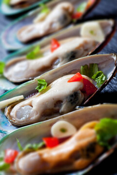 Green mussels with tomatoes, capsicum and garlic, on black slate slab