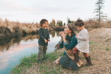 Maother and children playing with a grass blade at a river