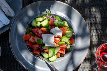 Summer healthy food served outdoor in sunlights, vegetable greek salad made with fresh cucumber, tomatoes, onion, feta cheese