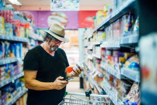 Senior man shopping in a supermarket using his smartphone