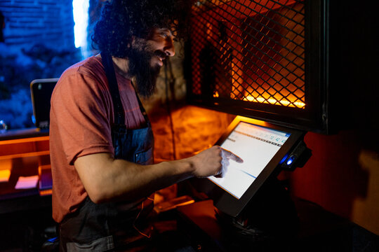 Young man, working in bar, using coputer cashier
