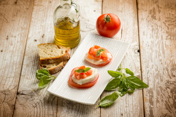 Caprese salad traditional italian recipe with mozzarella tomato basil and bread over white dish