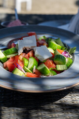 Summer healthy food served outdoor in sunlights, vegetable greek salad made with fresh cucumber, tomatoes, onion, feta cheese