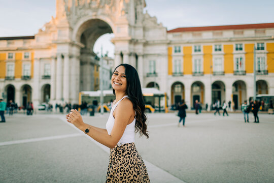 Portrait of happy young woman dancing in the city, Lisbon, Portugal