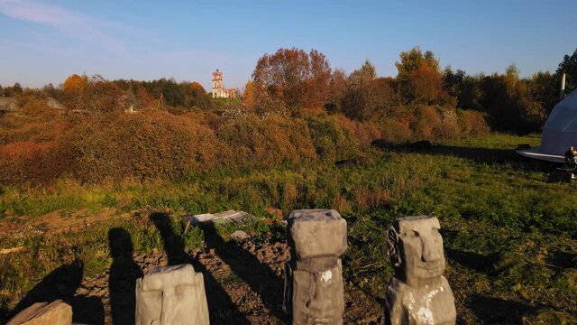 Replica of mysterioius moai statue from Easter Islands and old ruins of church in countryside. Models of Crooked Moais In Quarry from Rapa Nui Island.