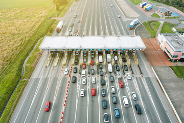 An overhead view of a busy toll road with many cars queuing up to pay the highway toll