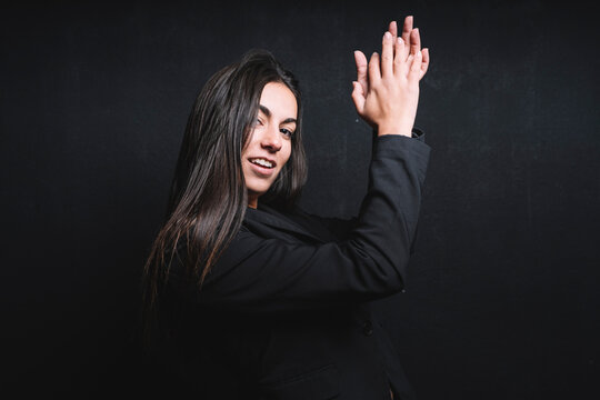 Portrait of smiling young woman clapping her handst in front of black background