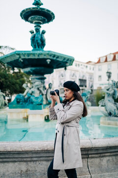 Young female traveller with camera at Rossio square's fountain, Lisbon, Portugal