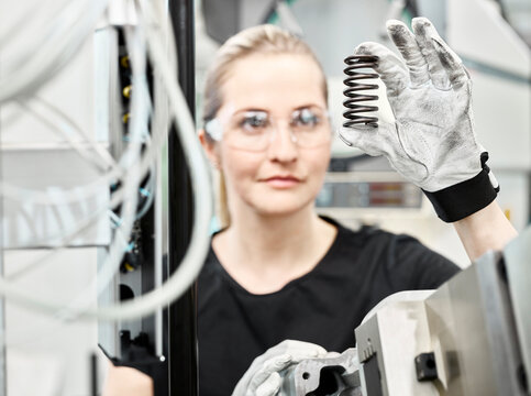 Woman working on a machine, looking on spring