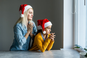 Lovely mother with daughter wearing Christmas holiday caps