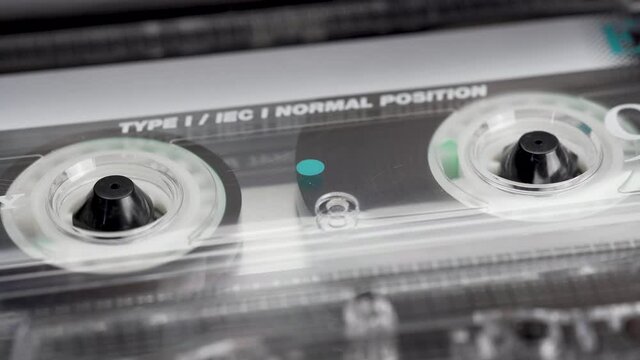 Audio cassette's tape reeling in an old audio recorder. Macro video of a rotating tape. 