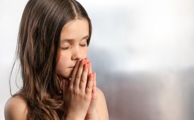 little child praying to God with hands together and a smile