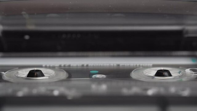 Audio cassette's tape reeling in an old audio recorder. Macro video of a rotating tape. 