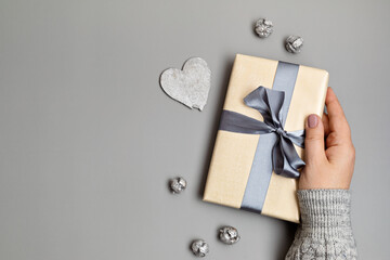 Christmas background with gift box in gray colors. Xmas celebration, greetings, preparation for winter holidays. Festive mockup, top view, flat lay with copy space