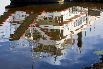 Fototapeta na wymiar Abstract photograph of a historic red, white and blue river boat reflecting in the blue water