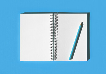Notebook with pencil. School notebook on light blue background, spiral notepad on table. Top view of open notebook with blank pages, office notepad flat lay. Two white Pages for your write