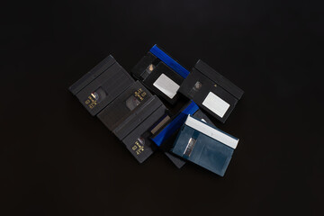 A pile of VHS-c cassettes on a black background. Retro video technology.