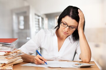 A young woman in eyewear paying household bills taxes or insurance, managing budget, calculating expenses.