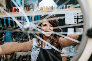 Beautiful young female mechanic having fun and enjoying while repairing bicycles in a workshop..