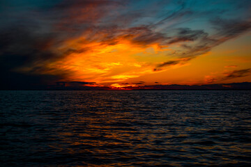 Fototapeta na wymiar Bright sunset over the water