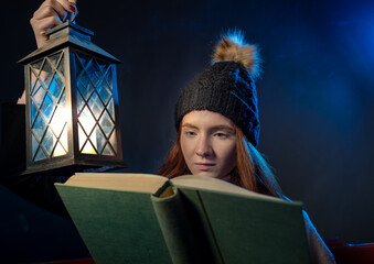 Girl reading old book on lantern light at night