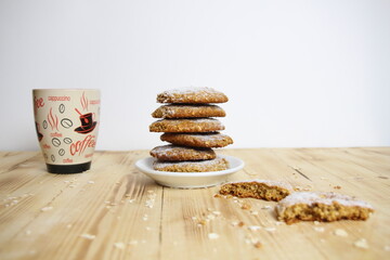 stack of oat cookies and cup of coffee on wooden background 