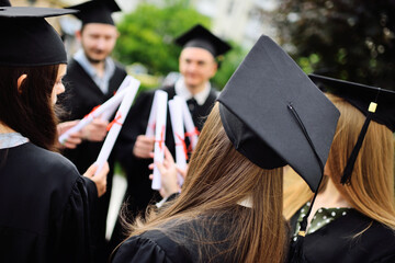 group of university graduates in student robes or mantle and square hats at the graduation ceremony...