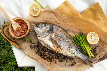 dorado fish baked on paper with sauce top view