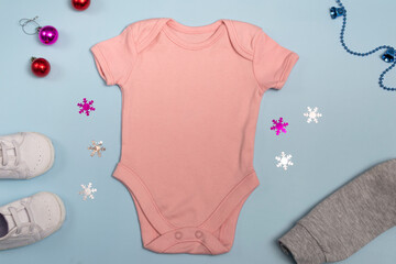Mockup of New Year's pink bodysuit on a blue background, decorated with white sneakers, red pants and Christmas tree decorations, top view