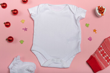 Mockup of New Year's white bodysuit on a pink background, decorated with white socks, red pants and Christmas tree decorations, top view