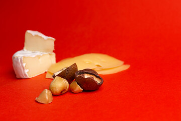 Camembert cheese with honey and macadamia nuts on a red background