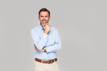 Photo of a smiling formal business man wearing a light blue shirt,  standing and looking at camera