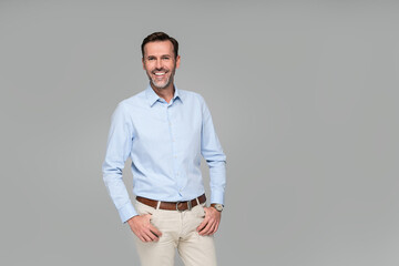 Photo of a smiling formal business man wearing a light blue shirt,  standing and looking at camera