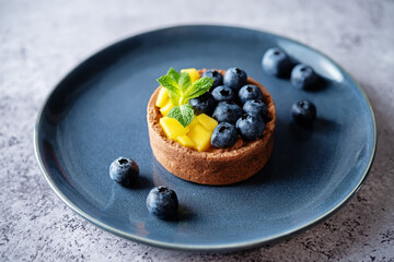 Chocolate tartlets with chocolate cream filling and mango fruit with blueberries