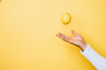 Studio shot of hand of person tossing up lemon