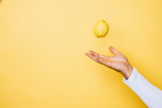 Studio shot of hand of person tossing up lemon