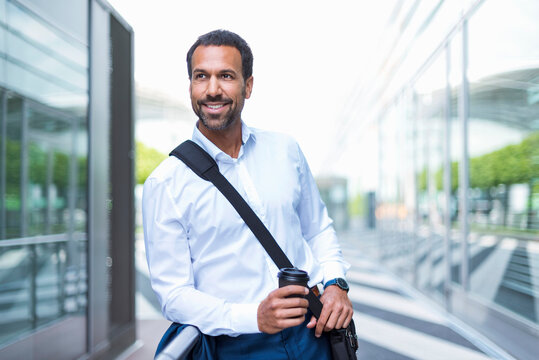 Businessman with coffee to go and laptop bag at airport