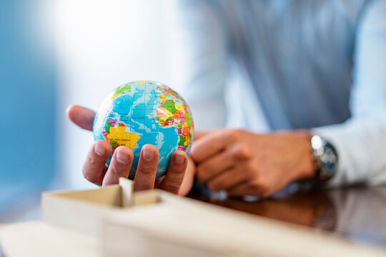 Close-up of businessman holding miniature globe in office